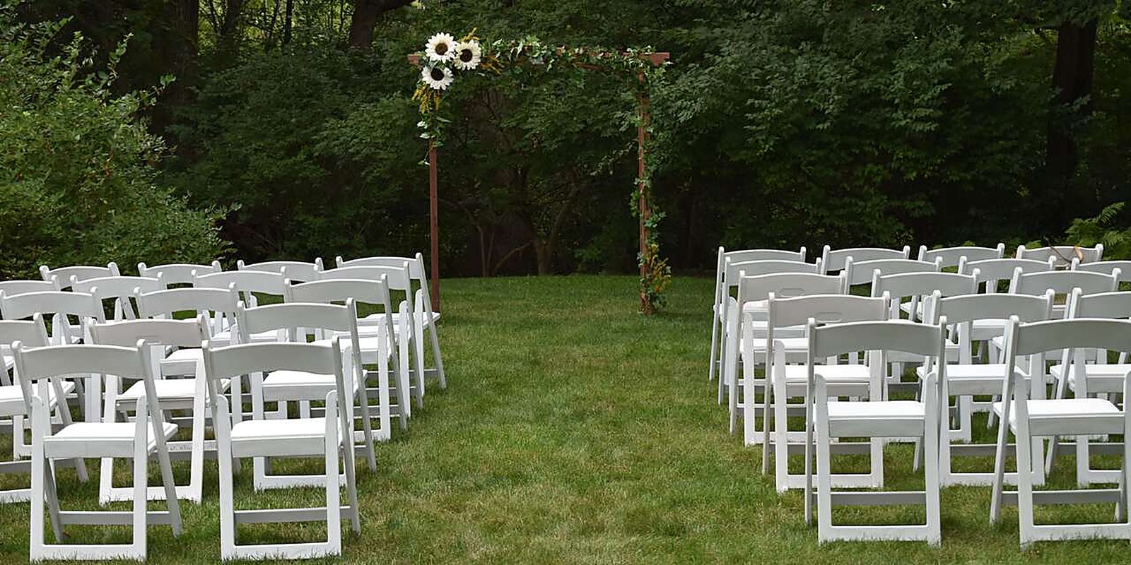 An outdoor ceremony on a Michigan lawn set with our white folding chairs