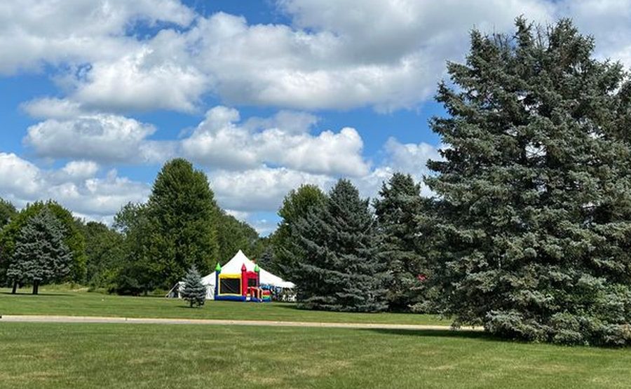 A white peaked tent and an inflatable set up on a Michigan lawn