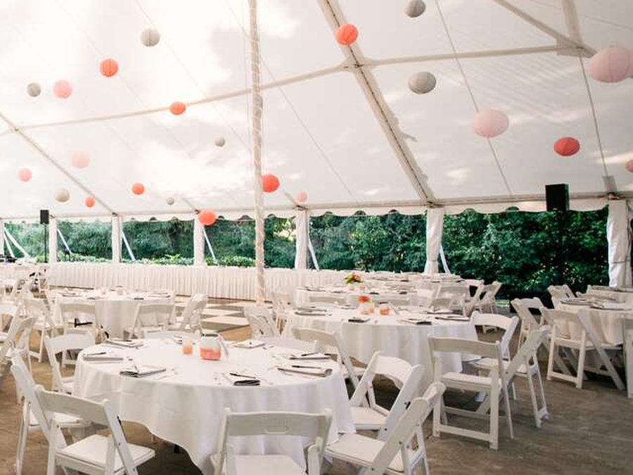 A tented reception with linened rounds and hanging lanterns